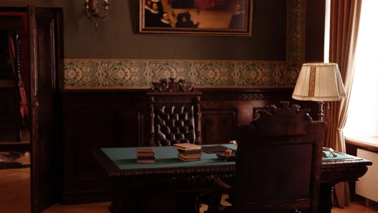 Dark wood executive office with a desk lamp and leather chairs