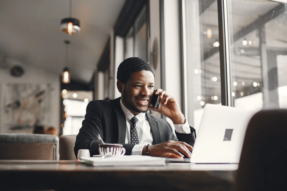 Smiling professional on a phone call at a laptop in a modern lounge
