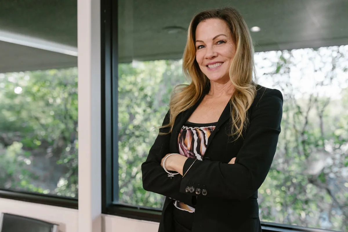 Confident professional in a black blazer standing by a window
