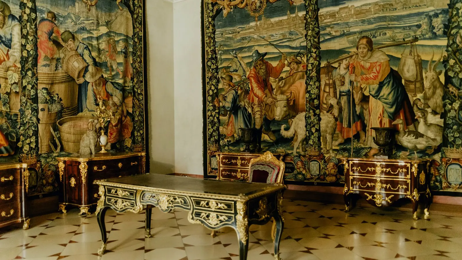 Renaissance tapestry room with a gilded writing table on a marble floor