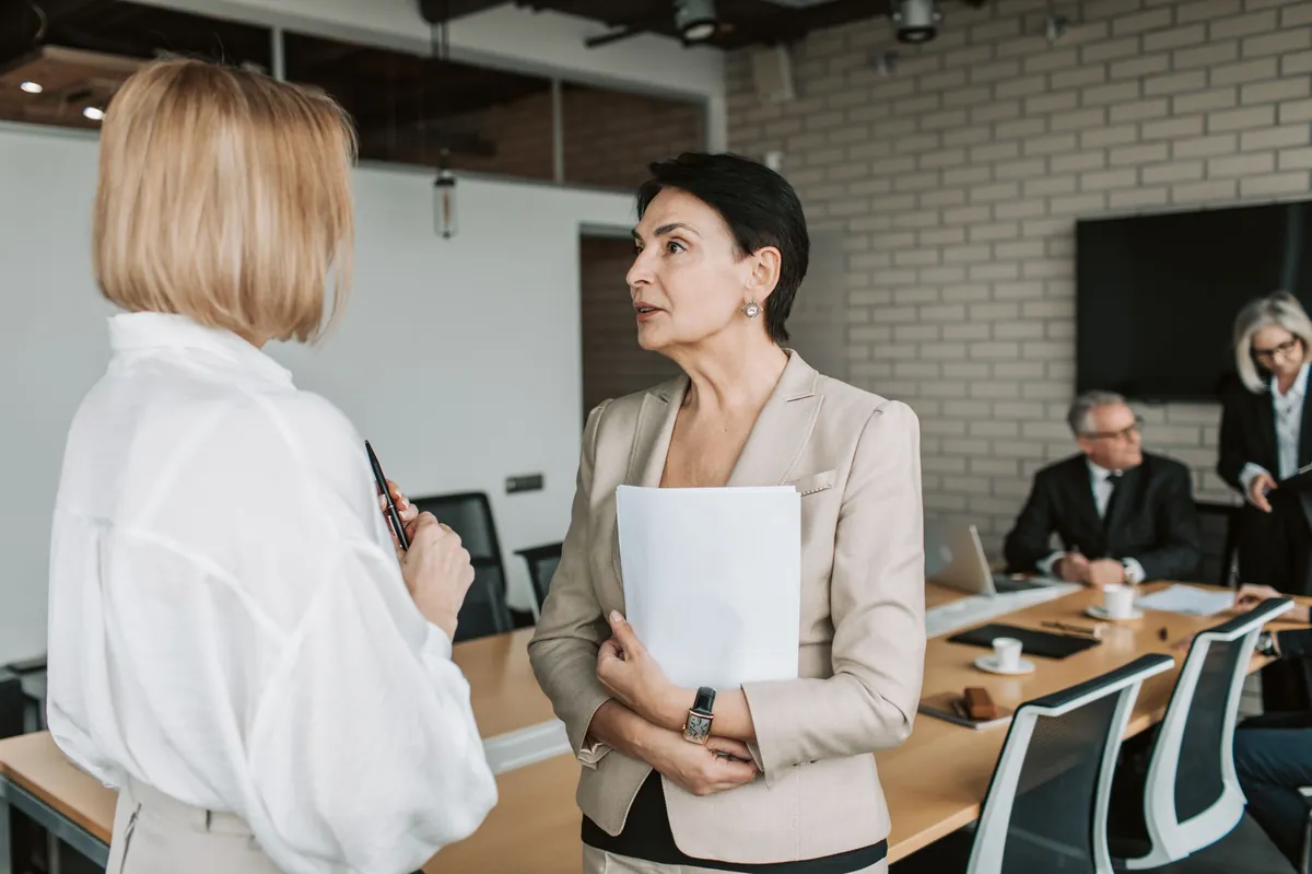 Two businesswomen in conversation during a meeting in a modern office