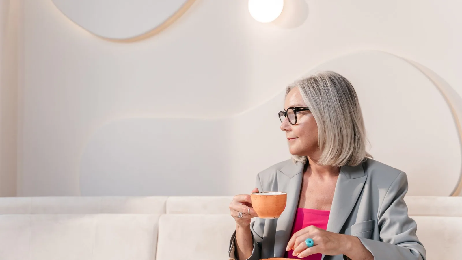 Woman in a blazer with coffee at a chic, minimal table
