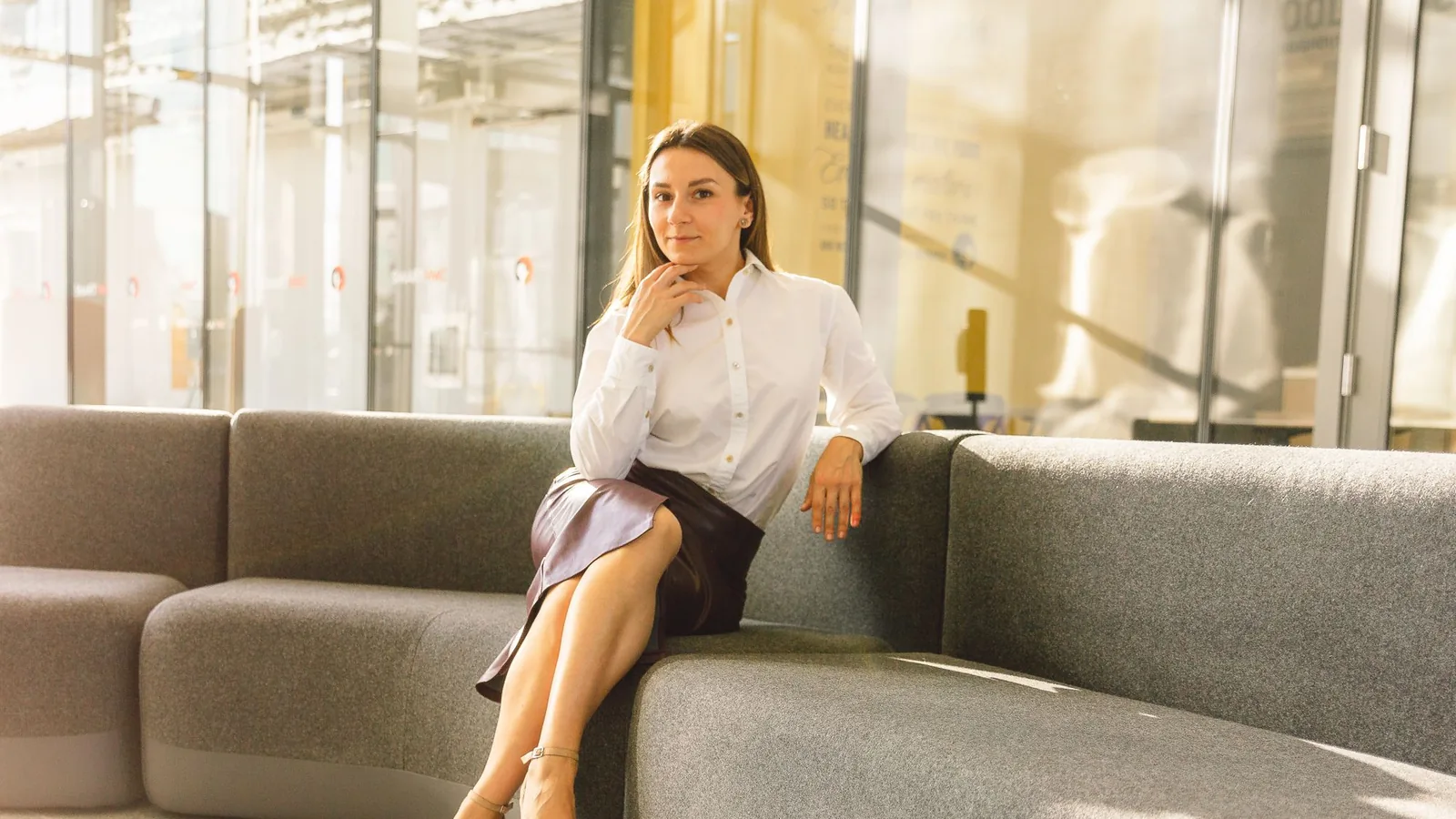 Professional woman seated on a modern sofa in a sunlit lounge