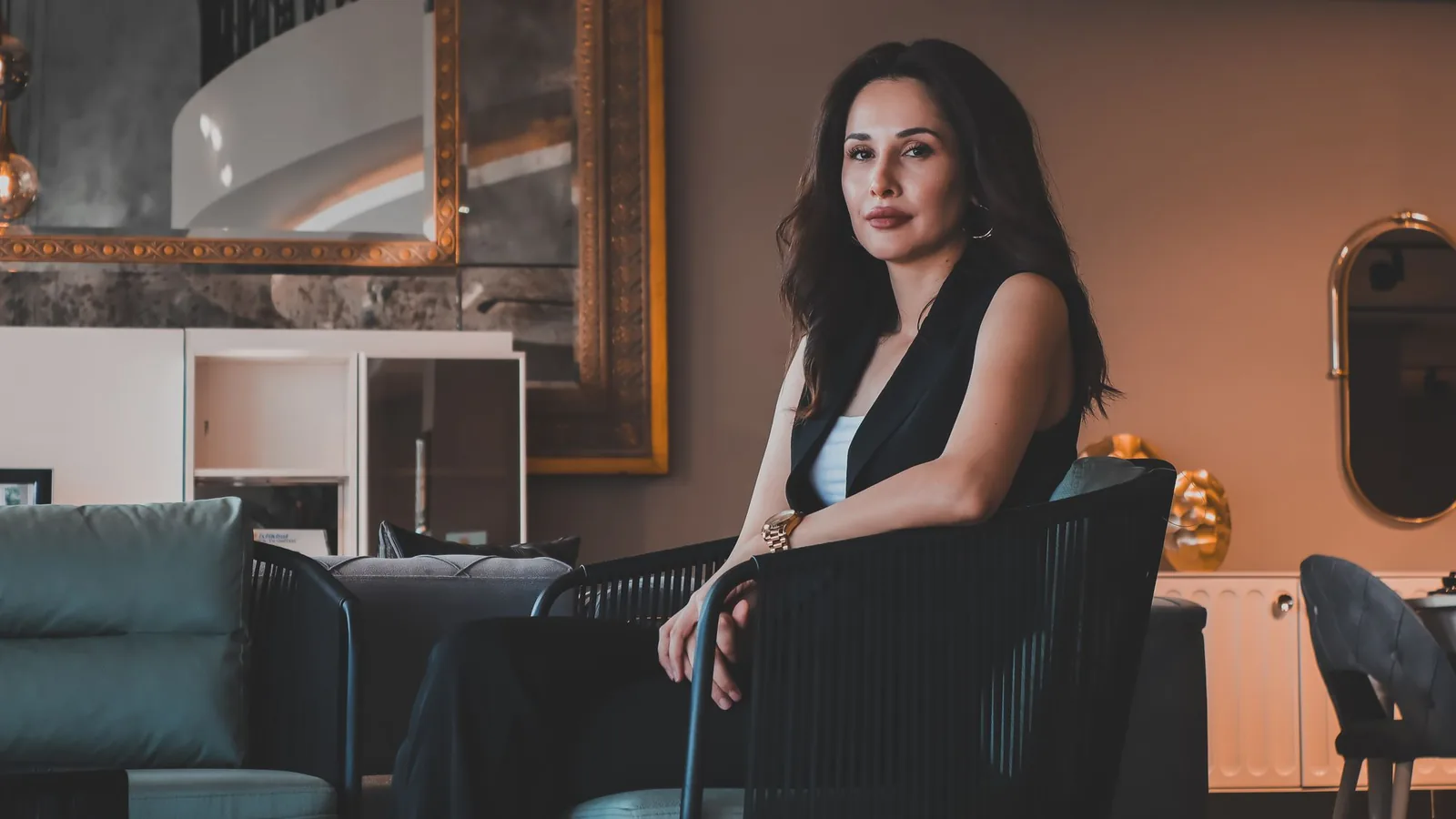 Confident woman seated in a luxe lounge with brass mirrors