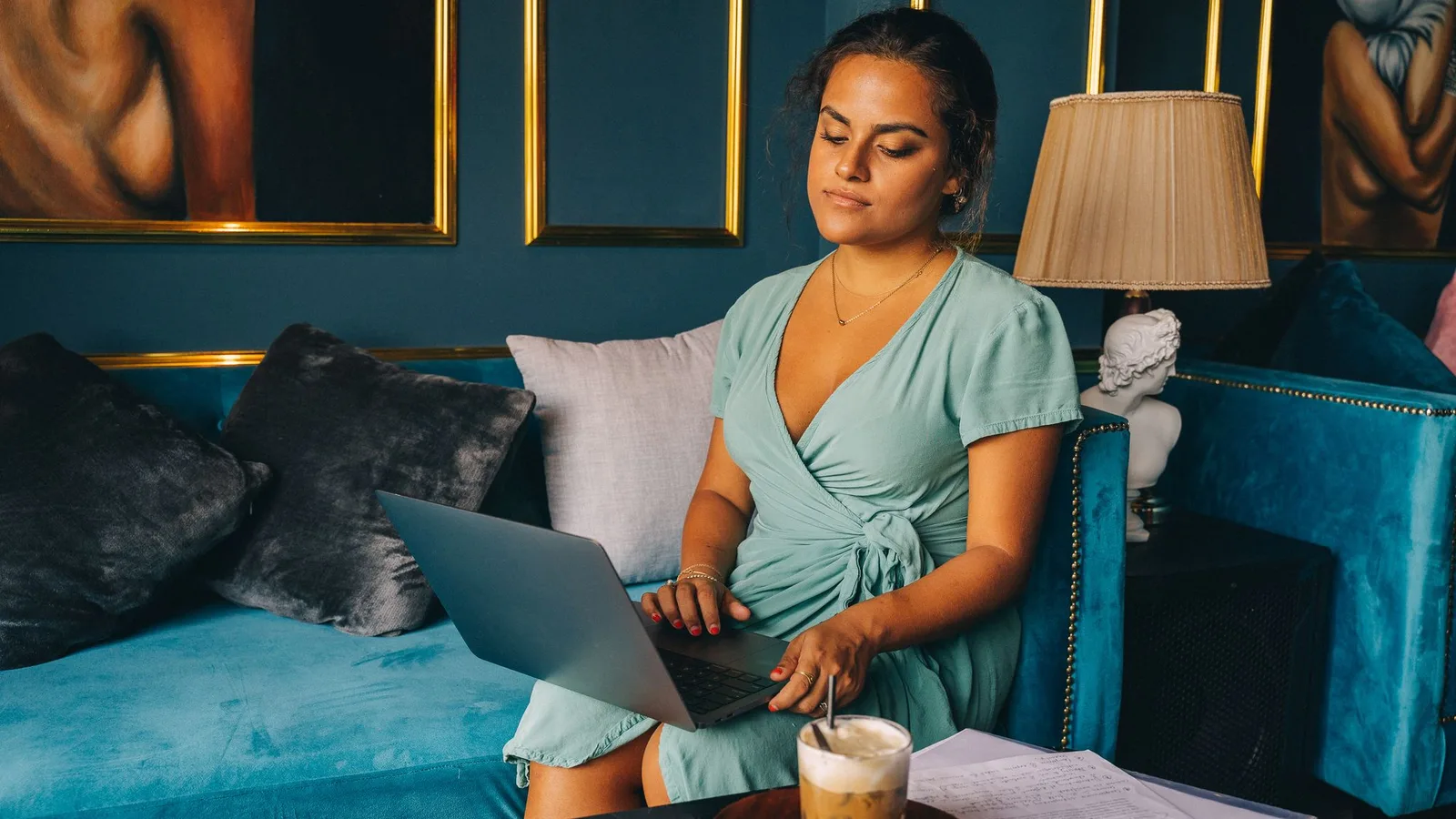 Practice owner planning her schedule on a laptop in a velvet and brass lounge