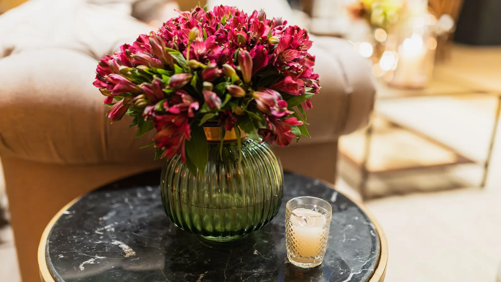 Fresh red florals on a marble side table in a warm, elegant lounge