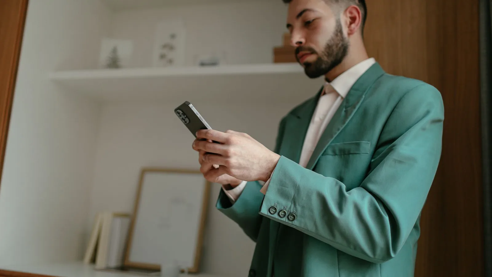 Practice owner in a tailored teal suit checking his iPhone in a warm, wood-panelled office