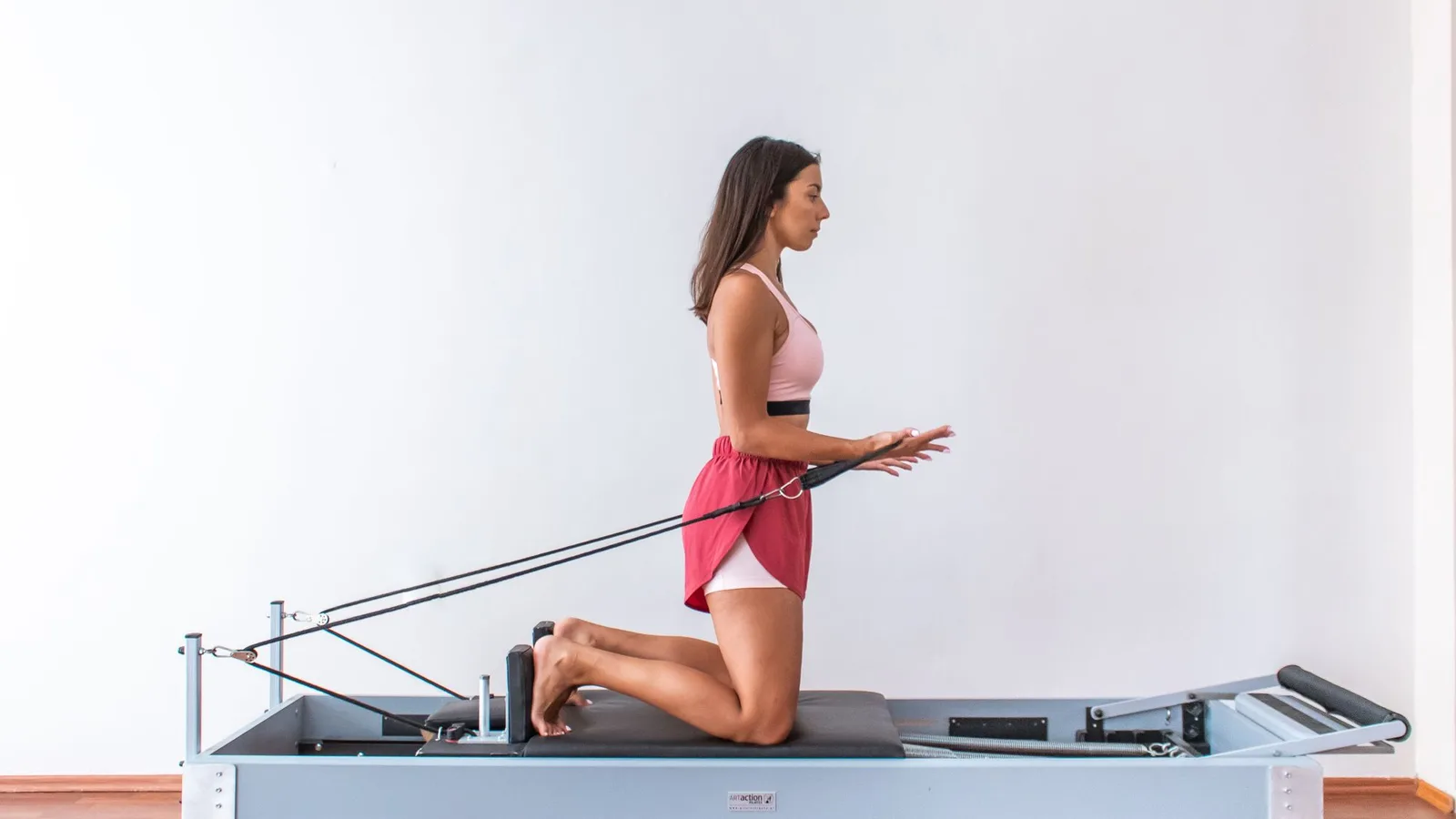 Woman training on a reformer in a clean, bright studio
