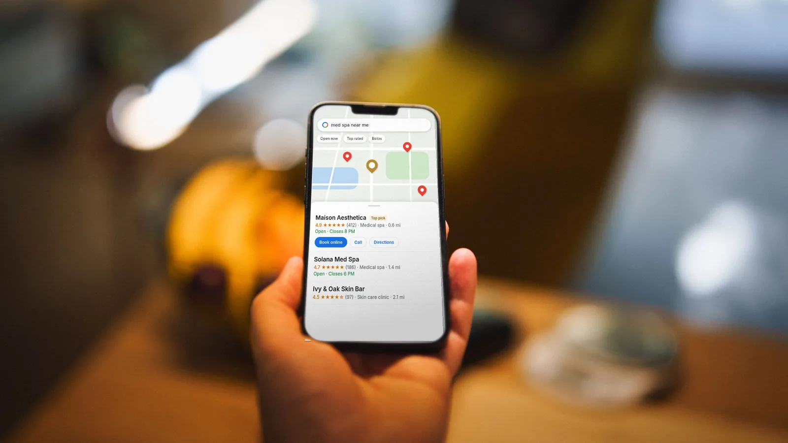 Hand holding an iPhone showing a Google Maps style local result for med spas (illustrative mockup, fictional businesses)