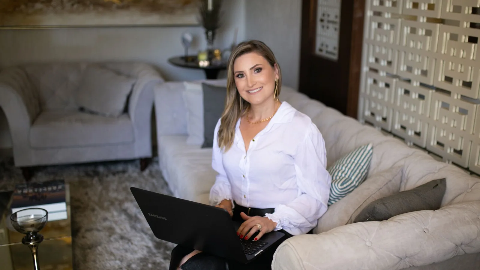 Owner in a silk blouse working on a laptop in a chic lounge