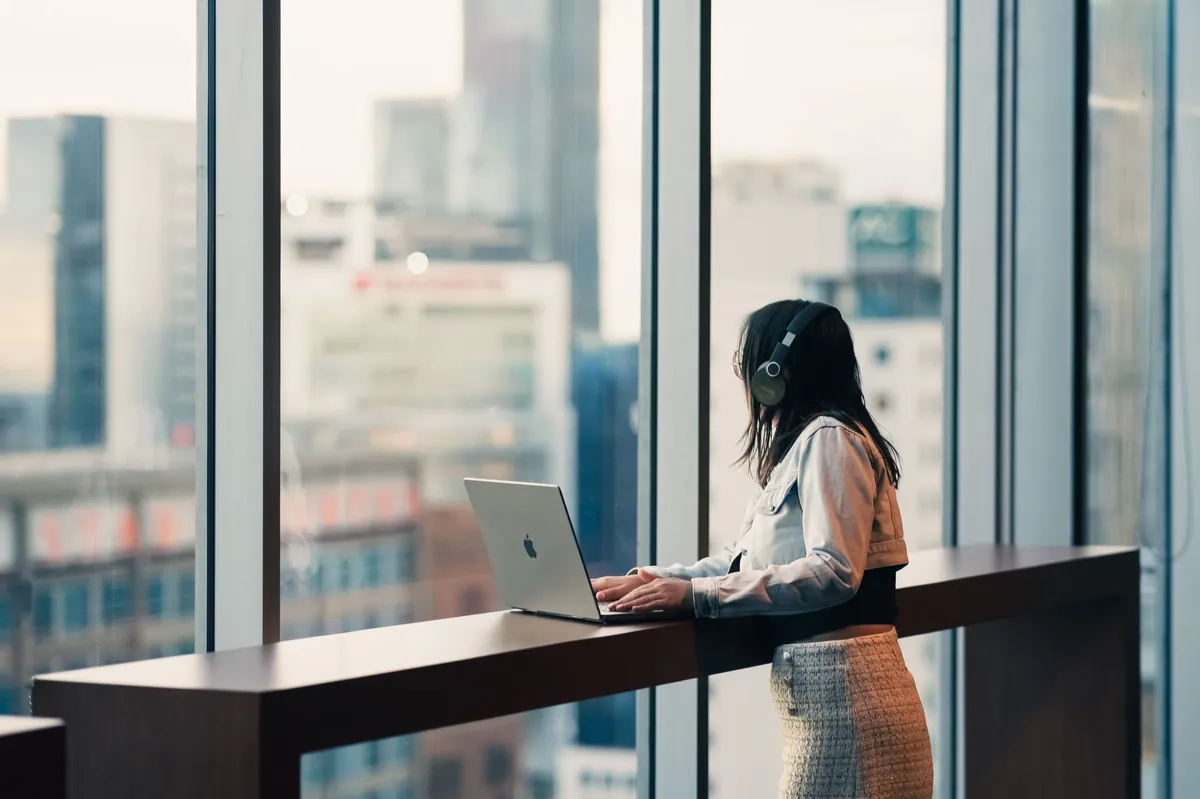 Professional working on a laptop at a window counter overlooking the city