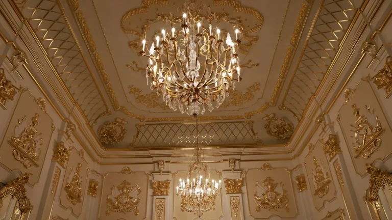 Ornate gold ballroom ceiling with two crystal chandeliers