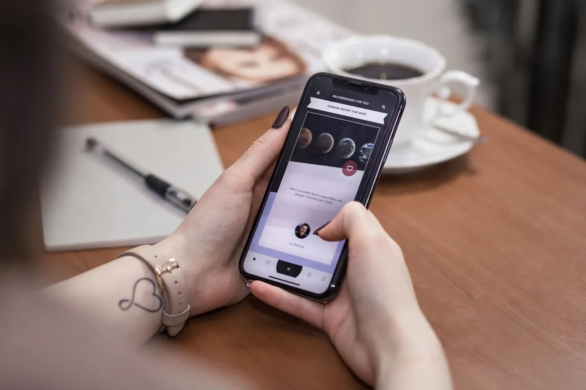 Person browsing on a smartphone at a cafe table with coffee