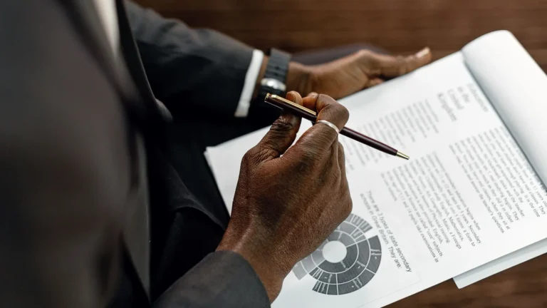 Hand holding a pen over a printed report with charts during a review