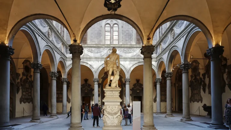 Florentine courtyard with stone arches, lanterns and a classical statue