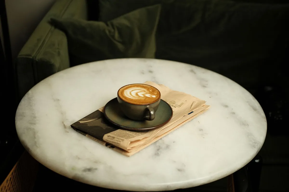 Latte on a round marble cafe table in a quiet green corner