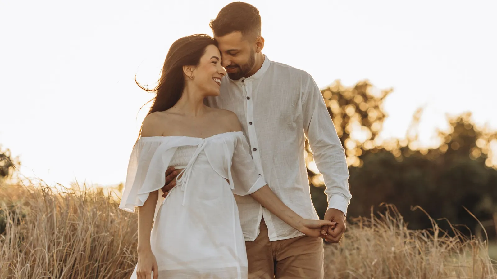 Couple in white embracing in a sunlit golden field