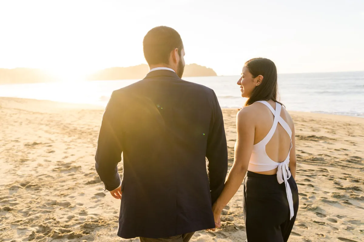Couple walking hand in hand along a beach at golden hour