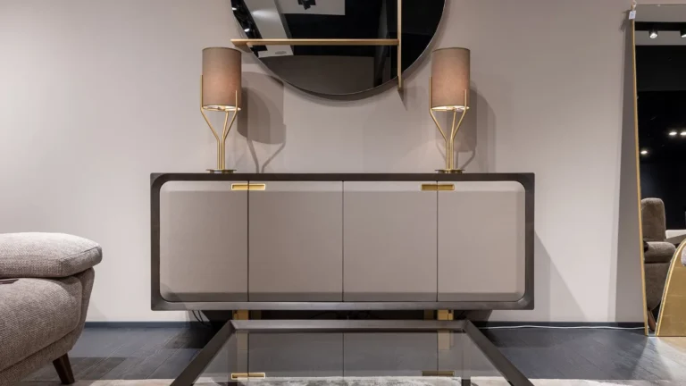 Modern console with brass lamps and a round mirror in a refined entry