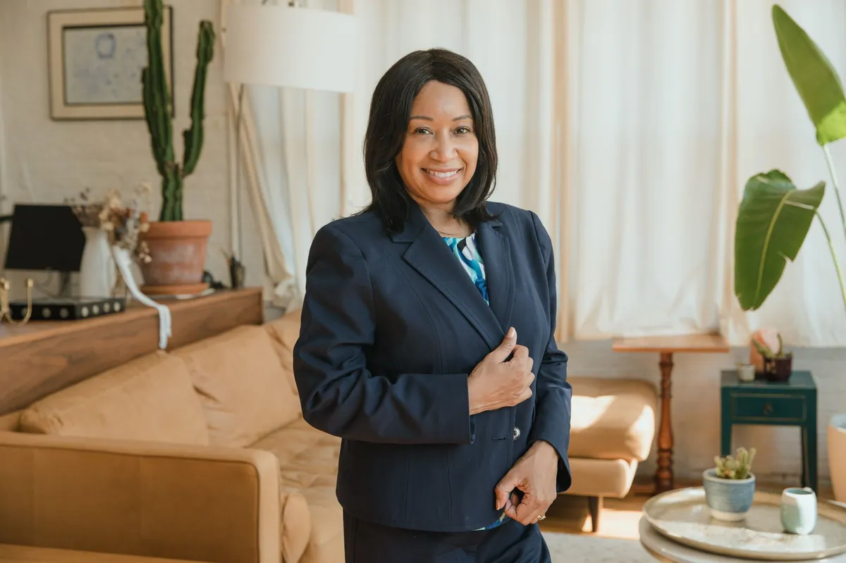 Professional in a navy suit standing in a warm, plant-filled office